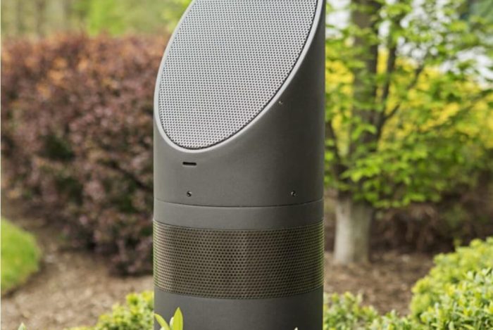 speaker shown outdoors with bushes